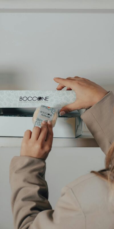A woman opening a Boccone box in a store setting, focusing on packaging.