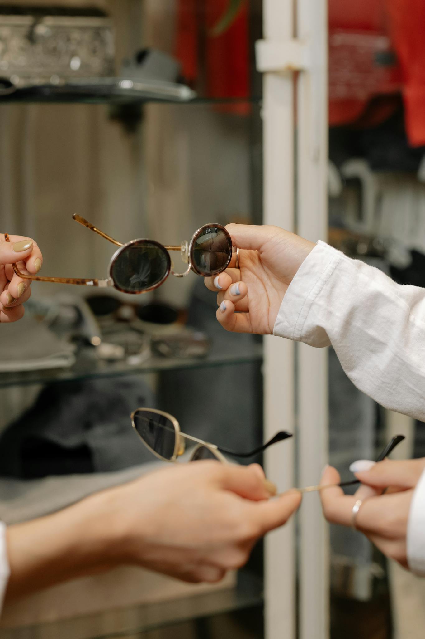 Close-up of hands holding sunglasses, exploring designs in a stylish fashion store.